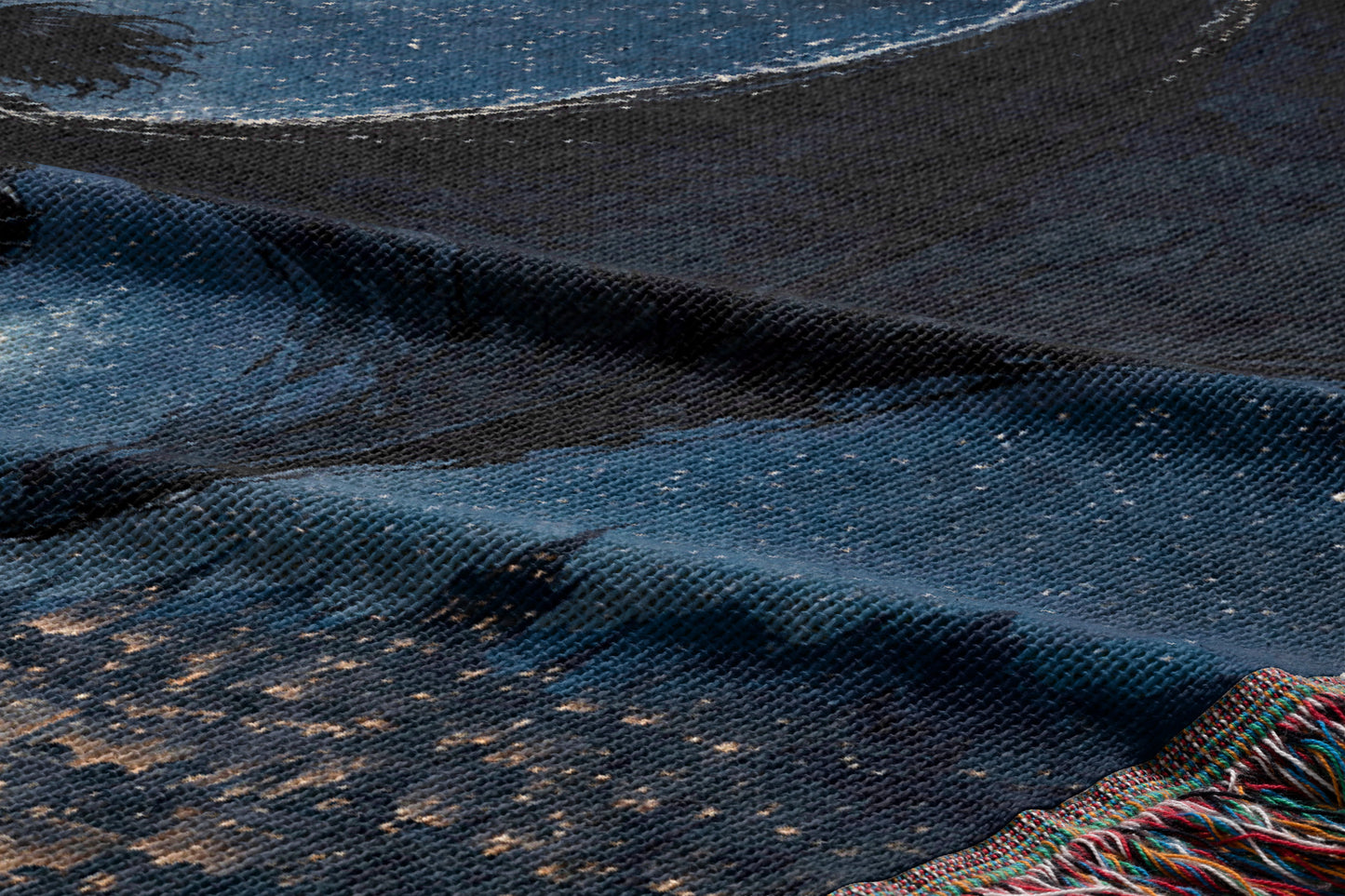 a close-up view of a textured fabric with a dark blue and black color scheme, featuring a pattern resembling a night sky or moon.