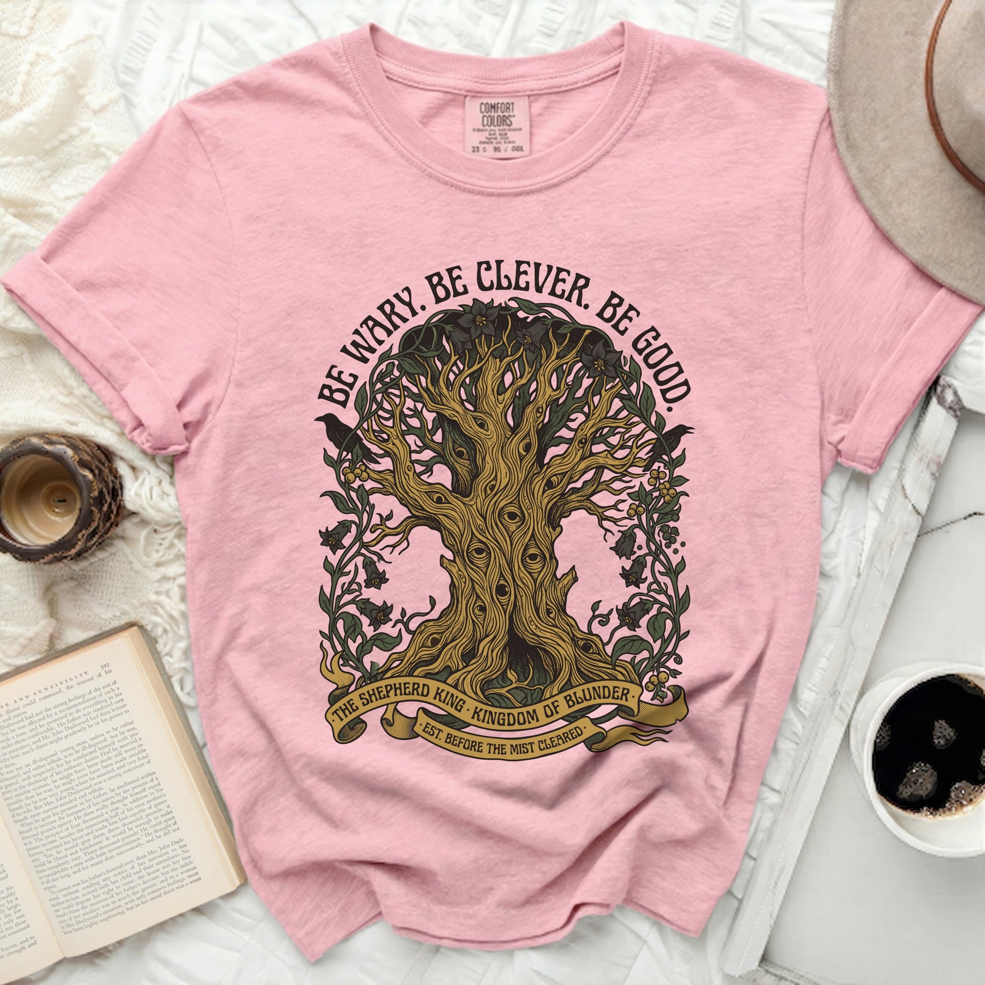 Pink t-shirt with "BE WARY. BE CLEVER. BE GOOD." text and tree design.