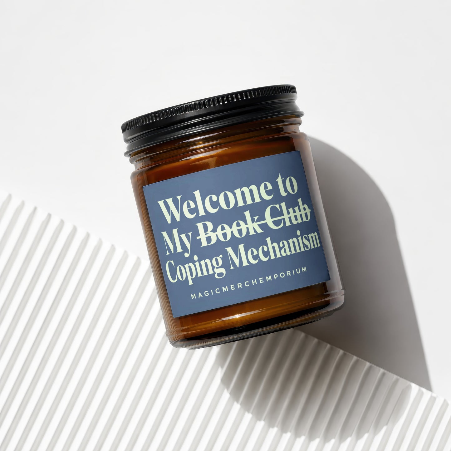 Amber jar candle with dark lid, reading "Welcome to My Book Club Coping Mechanism MAGICMERCH...".