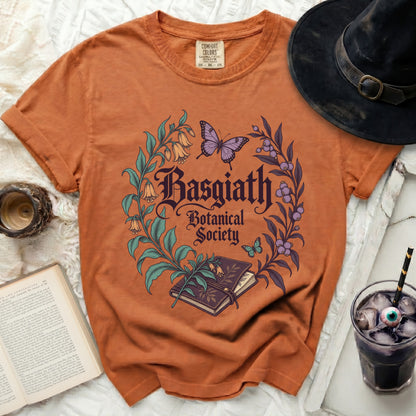 Orange t-shirt with "Basgiath Botanical Society" text and floral design.