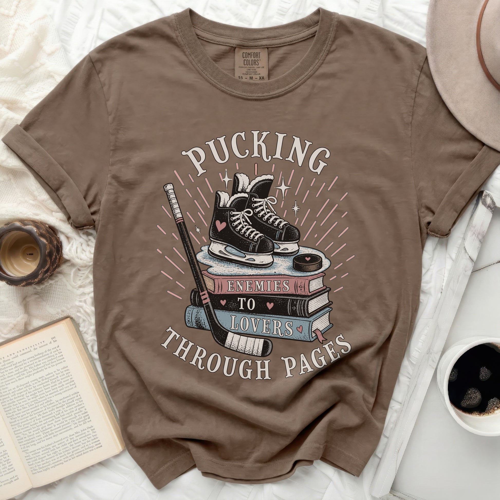 Brown t-shirt with "Pucking Through Pages" and ice skates graphic.
