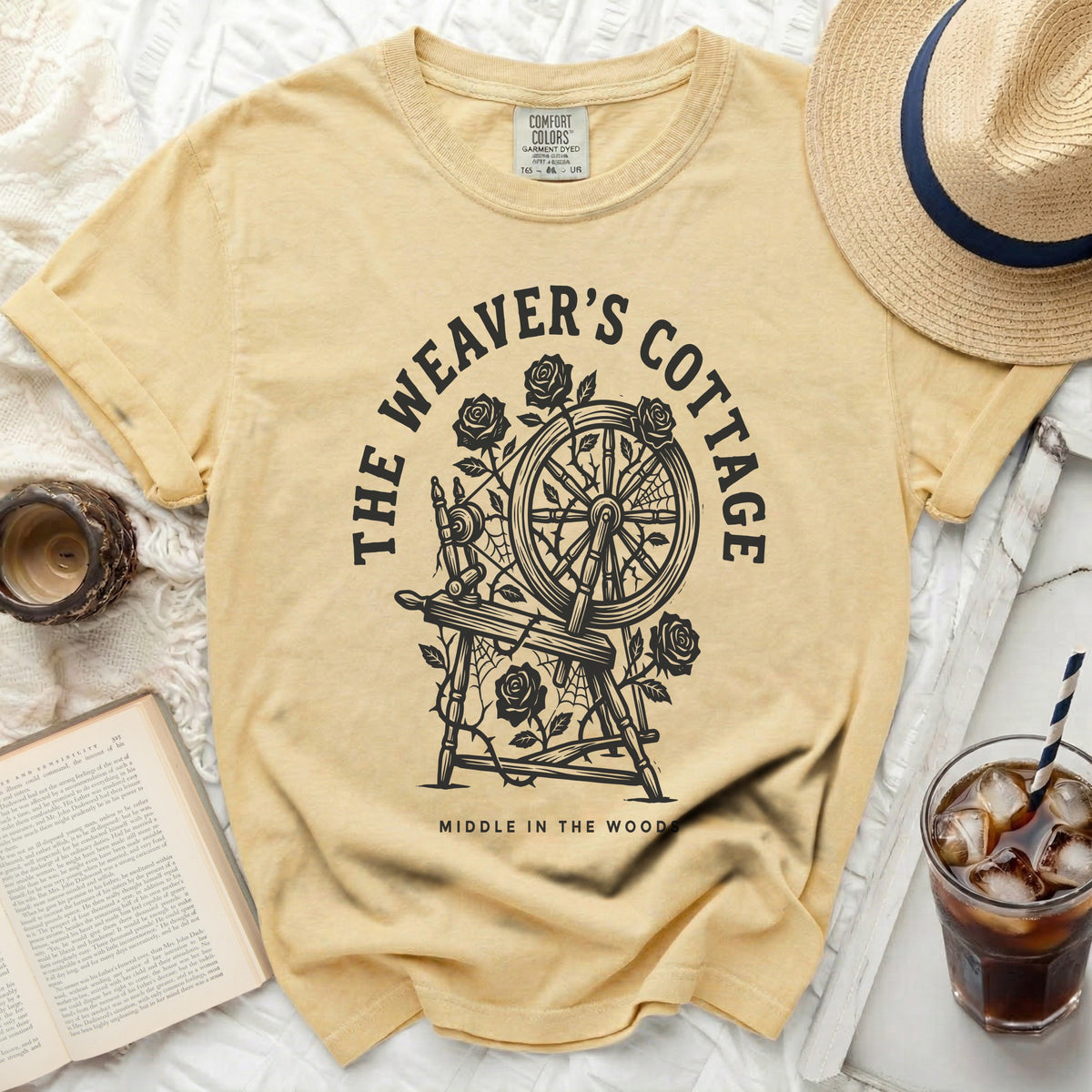 Yellow t-shirt with black graphic of a spinning wheel and roses, reading "THE WEAVER'S COTTAGE MIDDLE IN THE WOODS".