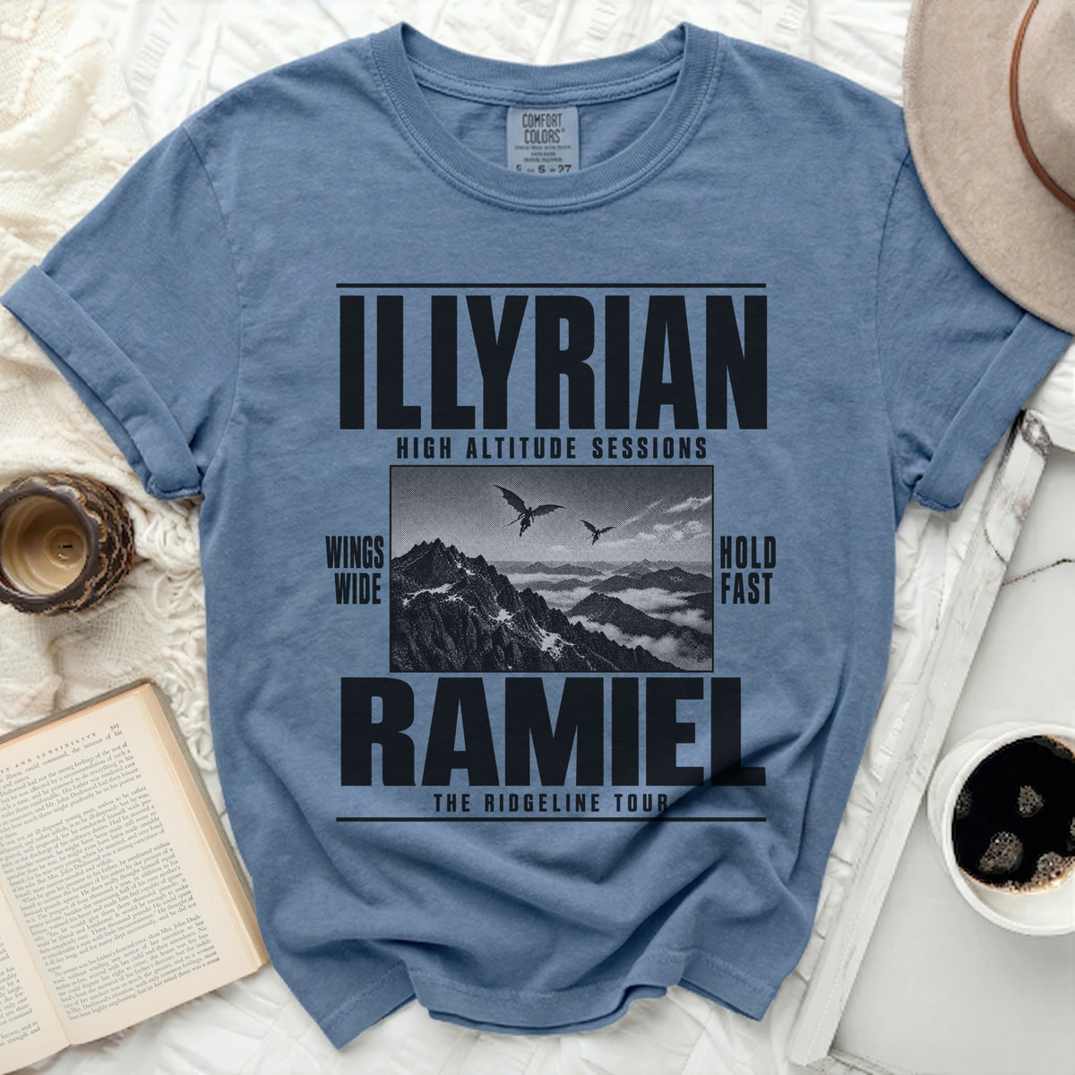 T-shirt with "ILLYRIAN HIGH ALTITUDE SESSIONS RAMIEL THE RIDGELINE TOUR" text and mountain art.