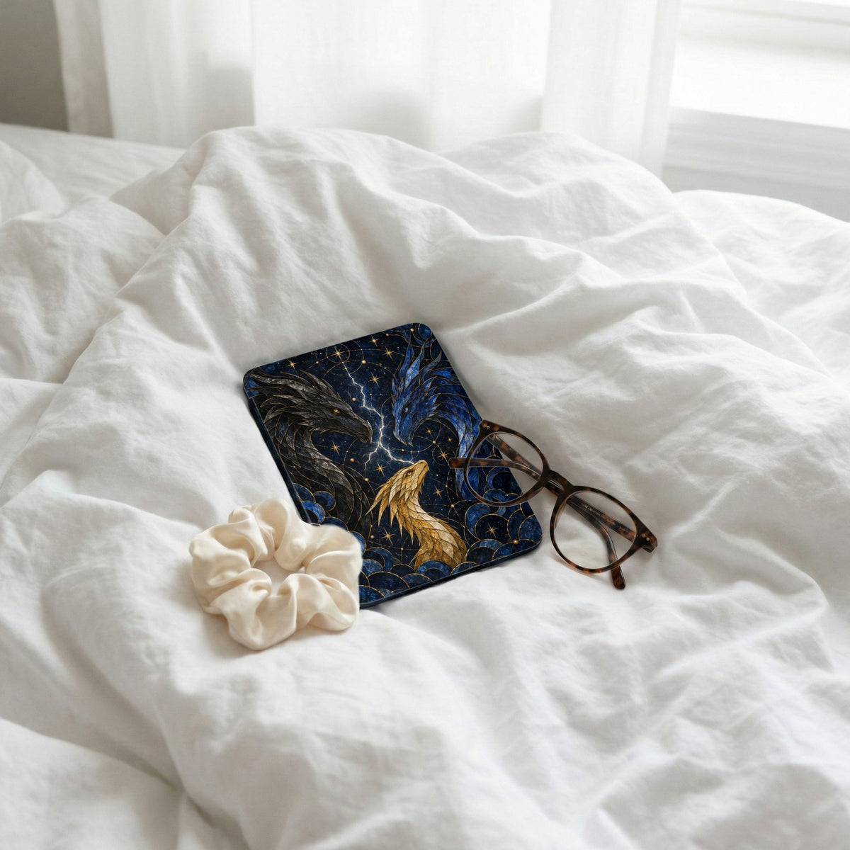 Case with three dragons and celestial pattern, next to glasses and scrunchie.