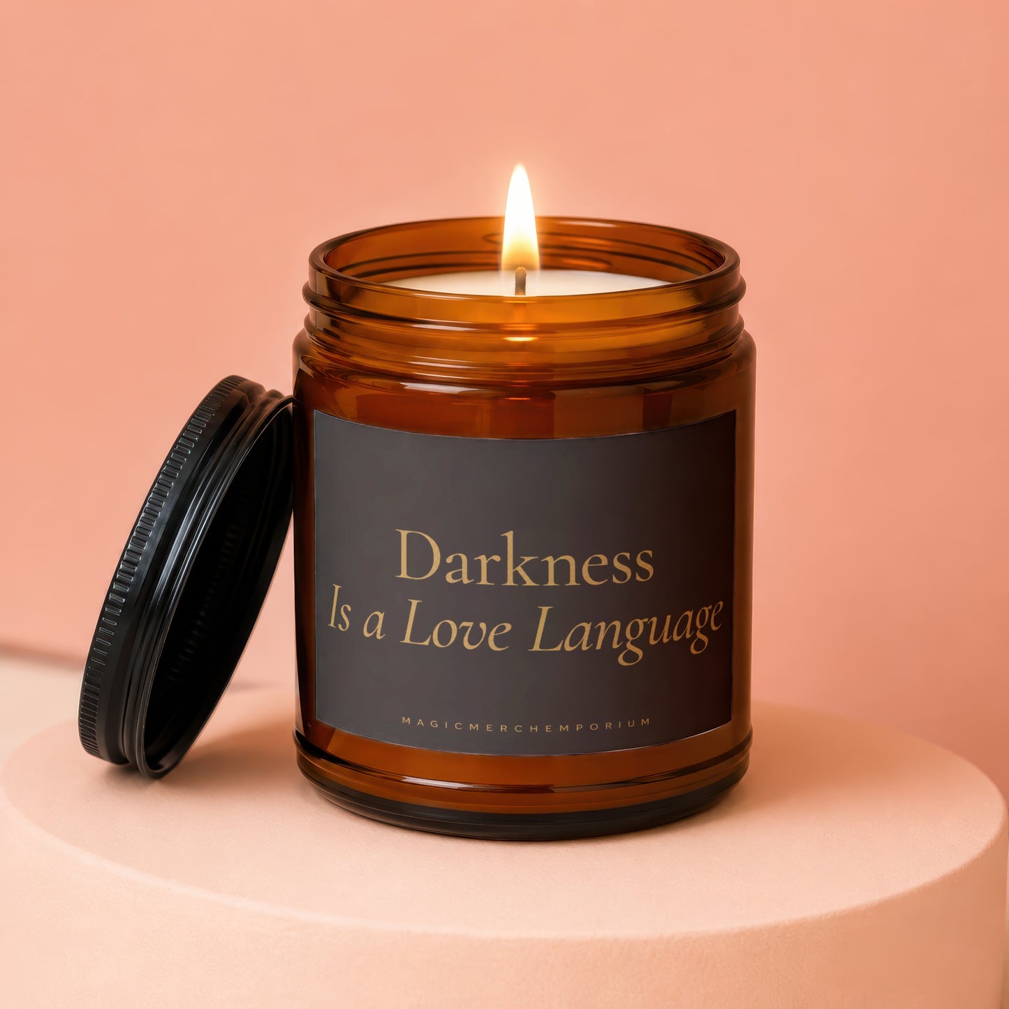 Amber jar candle labeled "Darkness Is a Love Language" with lit wick.