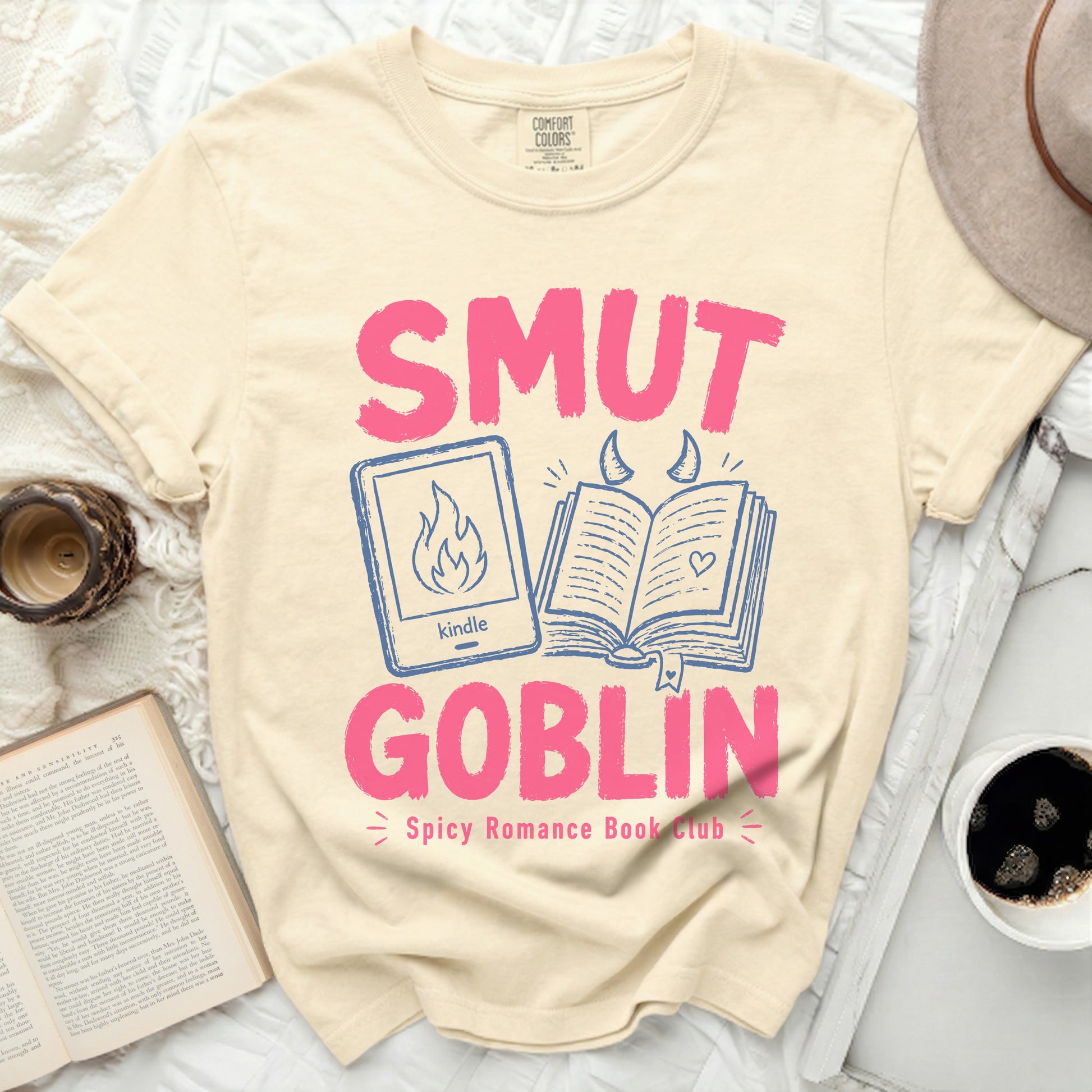 "Smut Goblin" text with kindle and book graphics on cream t-shirt.