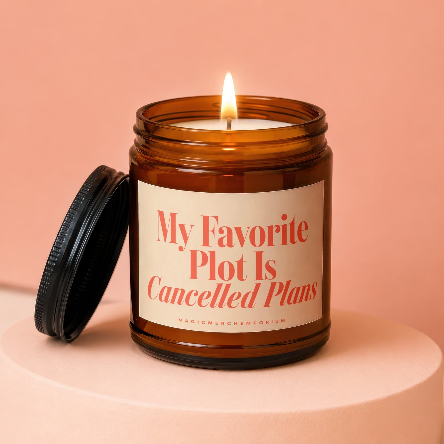 Amber jar candle with lit flame, reading "My Favorite Plot Is Cancelled Plans".