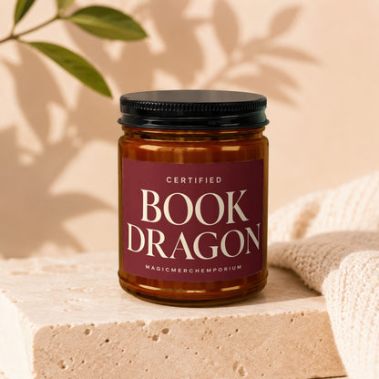 Amber jar candle labeled "Certified Book Dragon" with "MagicMerchEmporium" below.