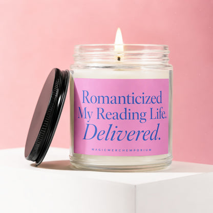 A lit candle in a glass jar with a pink label reading "Romanticized My Reading Life. Delivered."