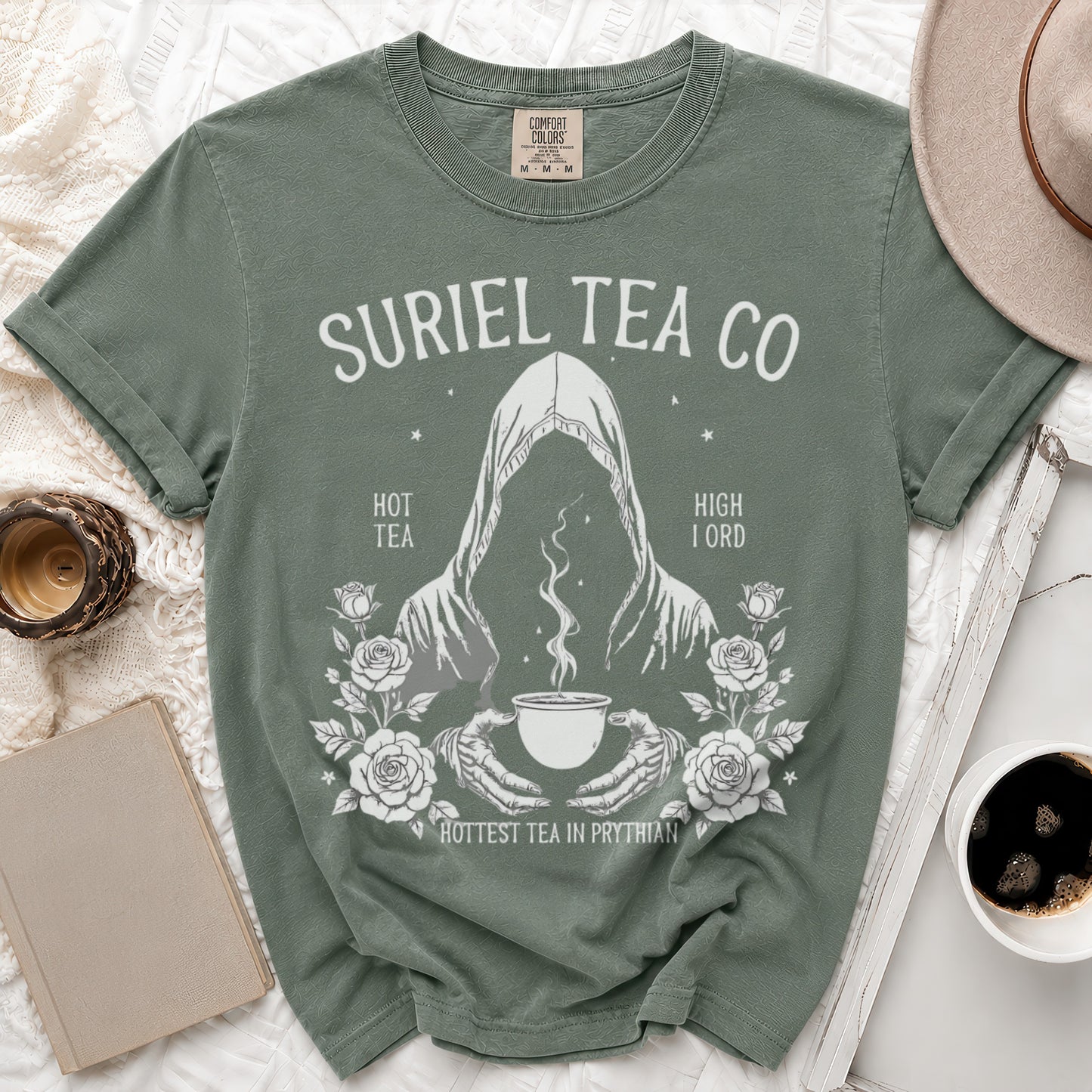 Green t-shirt with Suriel Tea Co. logo featuring a hooded figure holding a steaming teacup.
