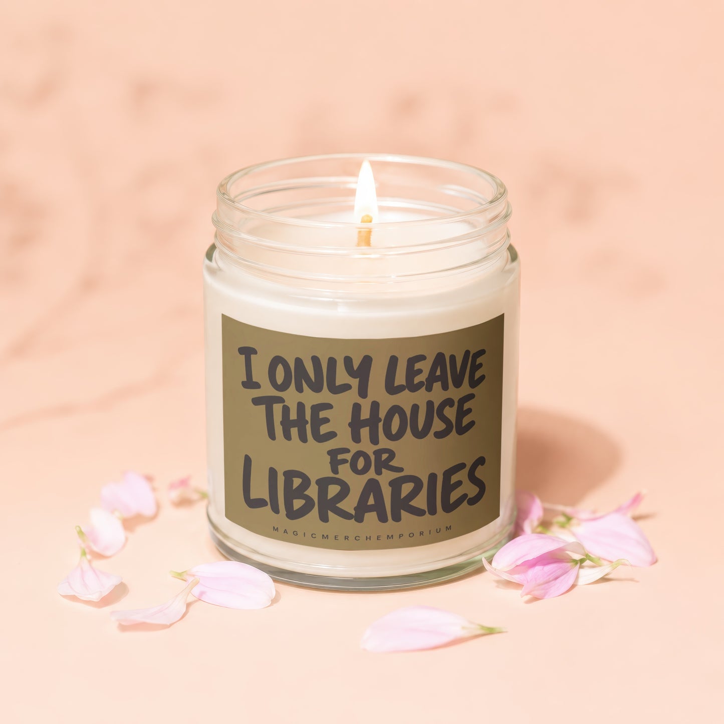 Glass jar candle with lit wick, labeled "I ONLY LEAVE THE HOUSE FOR LIBRARIES."