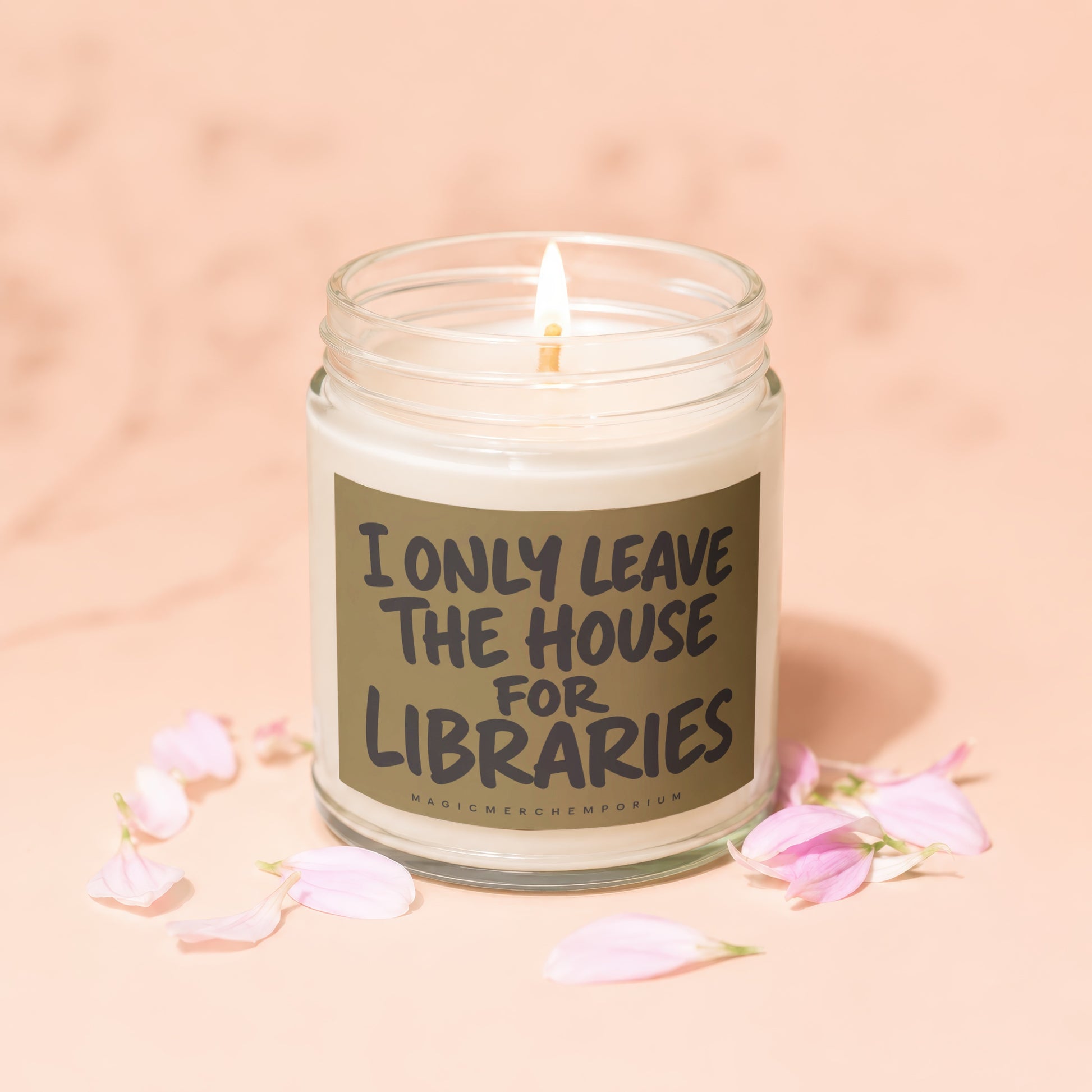 Glass jar candle with lit wick, labeled "I ONLY LEAVE THE HOUSE FOR LIBRARIES."