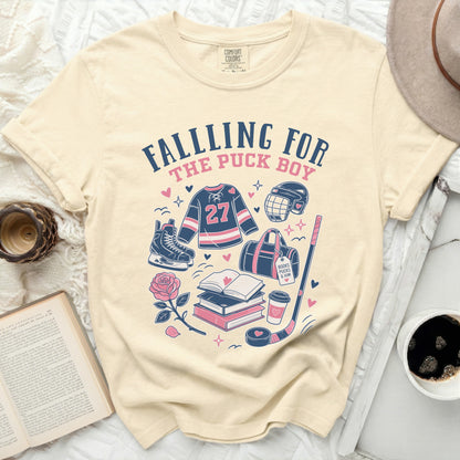 Cream comfort colors t-shirt with "Falling for the Puck Boy" hockey graphics.