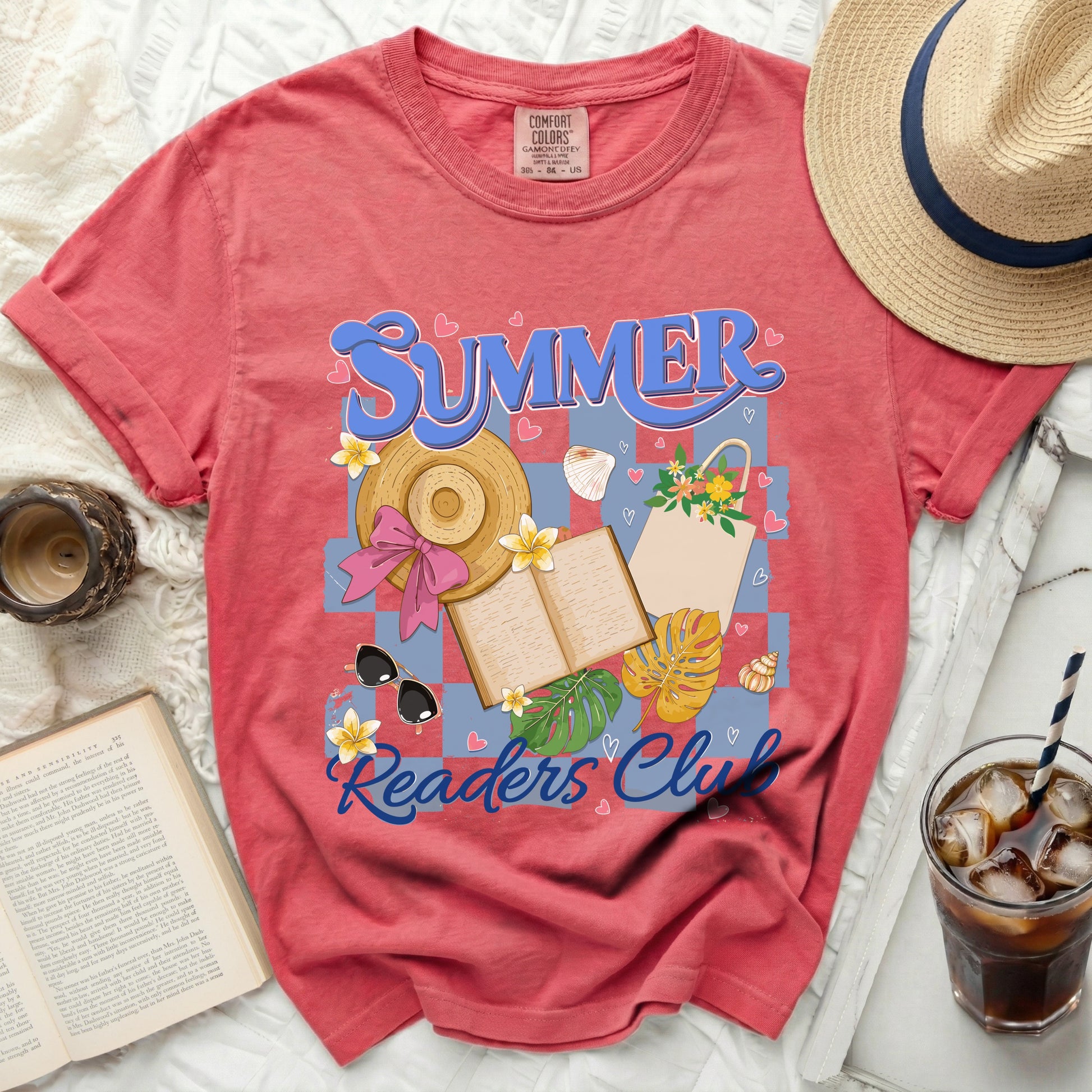 Coral t-shirt with "Summer Readers Club" graphic, hat, book, and drink.