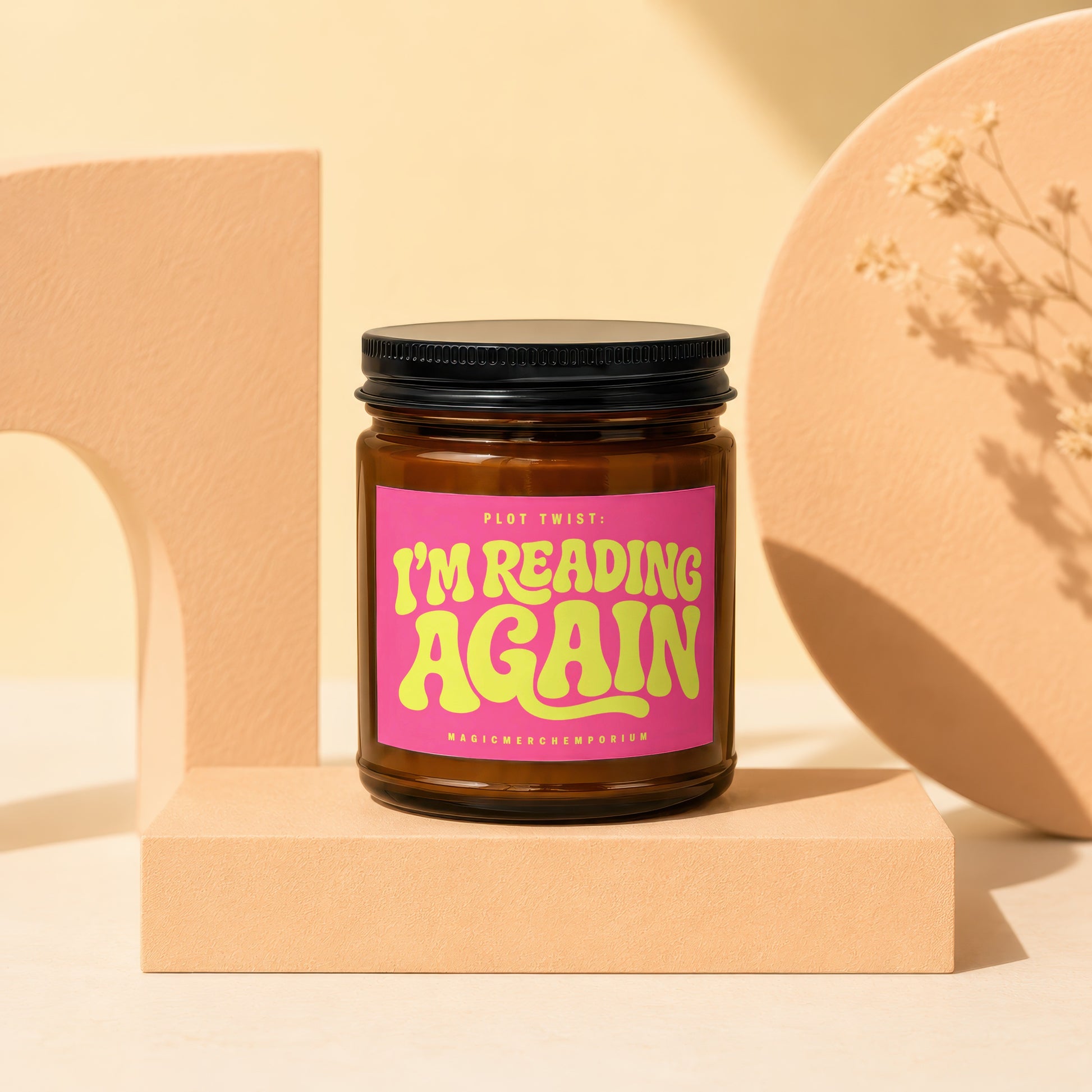 Brown glass candle with pink label reading "PLOT TWIST: I'M READING AGAIN".