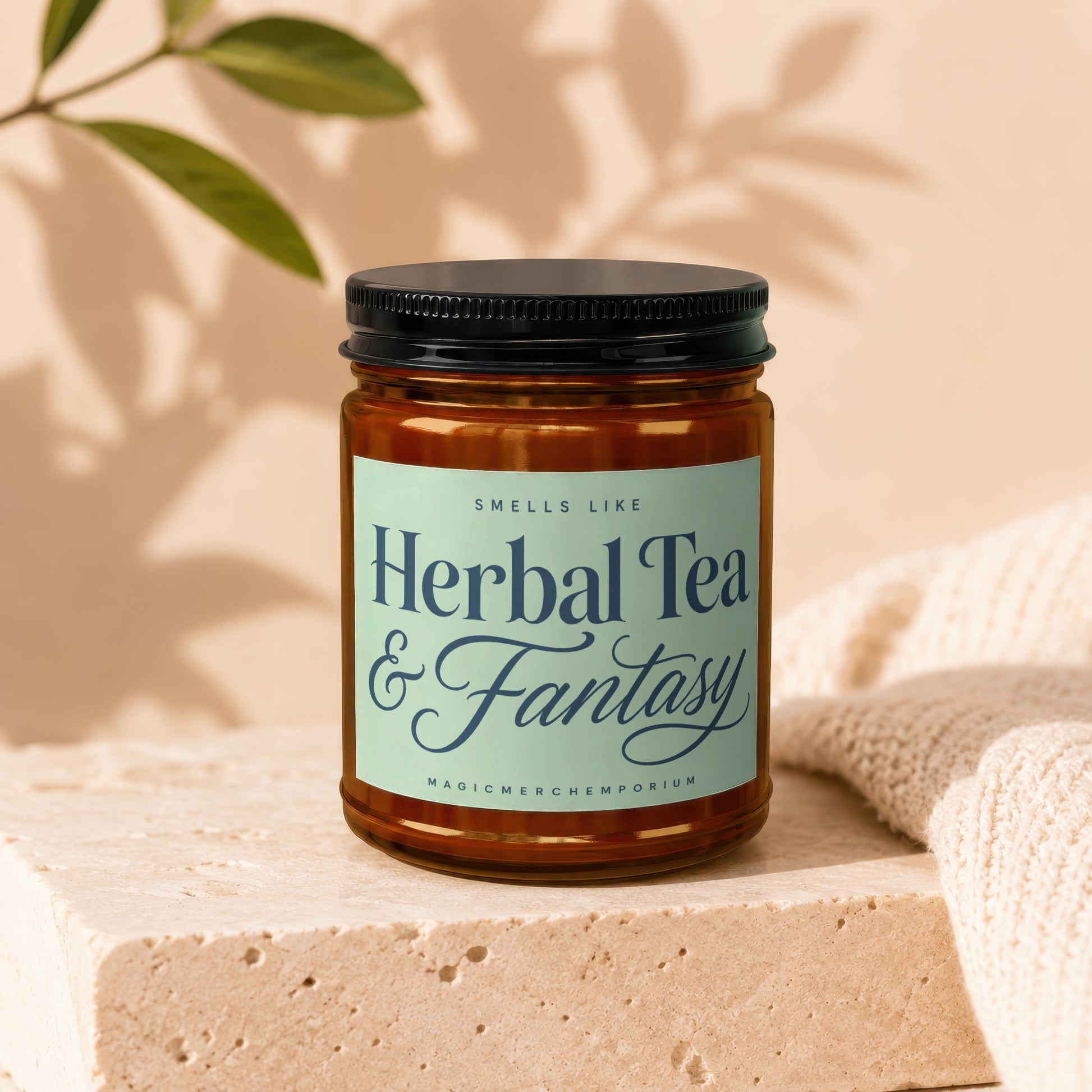 Amber jar candle with a light green label reading "Herbal Tea & Fantasy".
