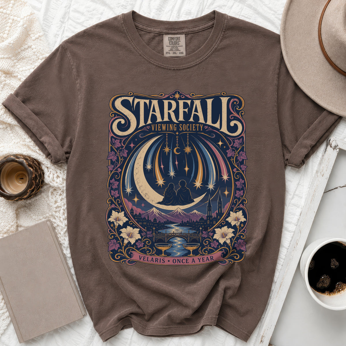 Brown t-shirt with a Starfall Viewing Society graphic featuring a couple on a crescent moon.