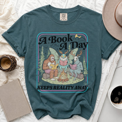 Graphic t-shirt with "A Book A Day Keeps Reality Away" text and forest creatures reading.