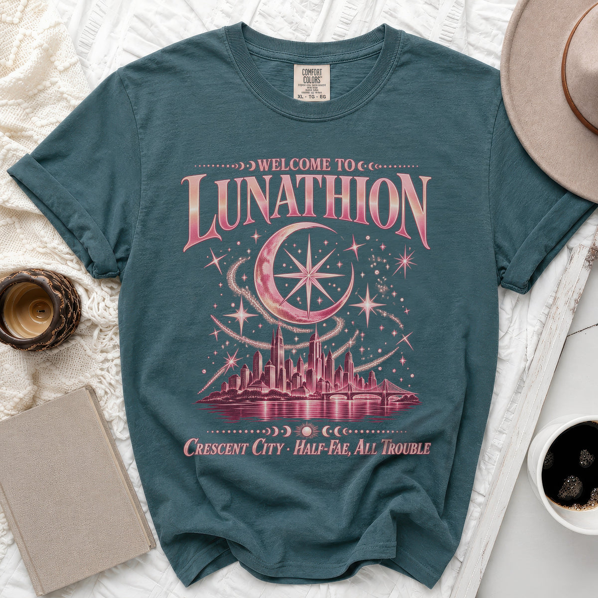 Teal t-shirt with "Welcome to Lunathion Crescent City Half-Fae, All Trouble" text and celestial cityscape.