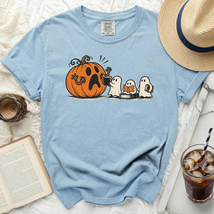 Blue t-shirt with a cartoon print of a surprised pumpkin and three ghosts reading books.