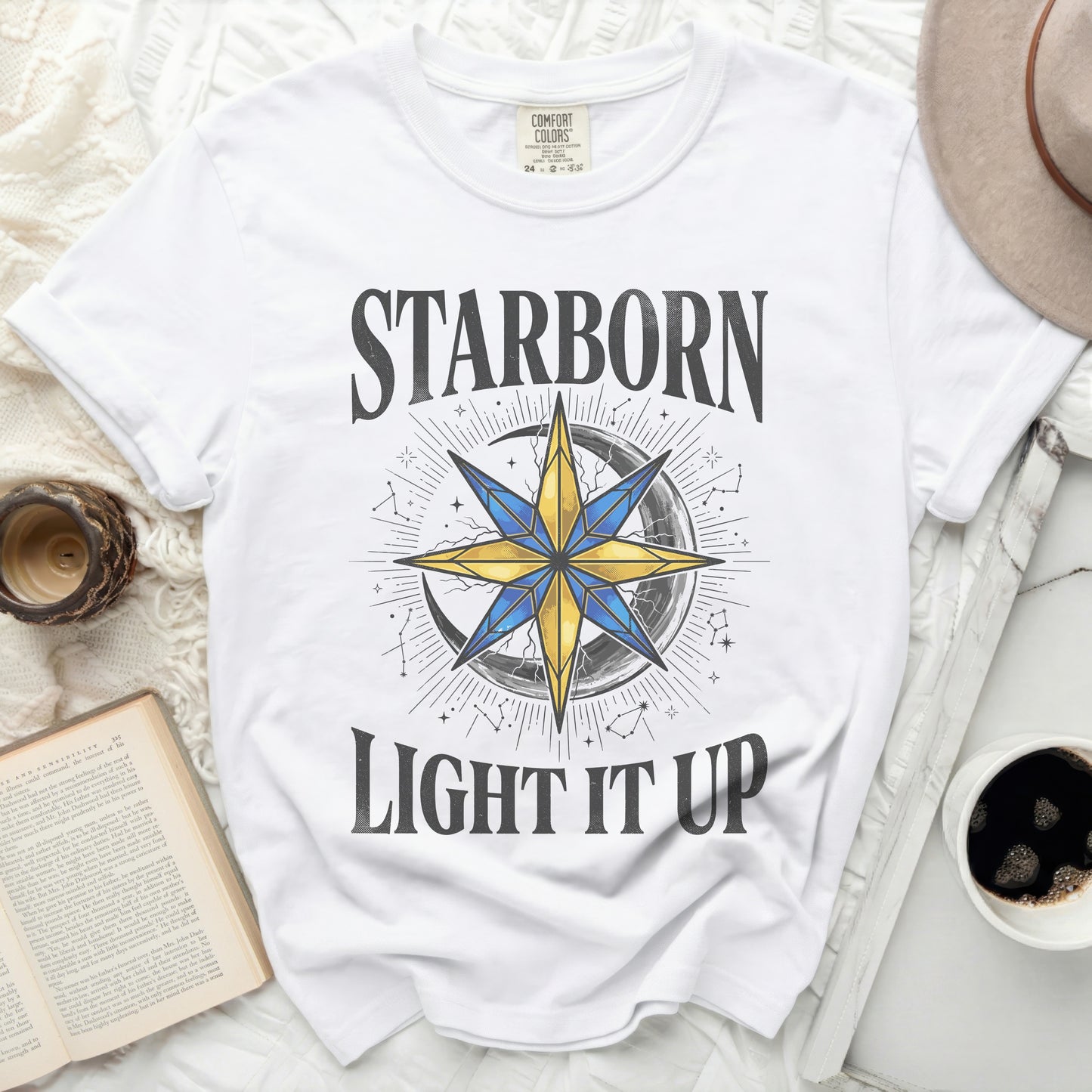 White t-shirt with "STARBORN LIGHT IT UP" text and celestial design.