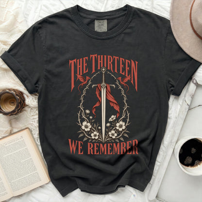 Dark t-shirt with "THE THIRTEEN WE REMEMBER" text and sword design.