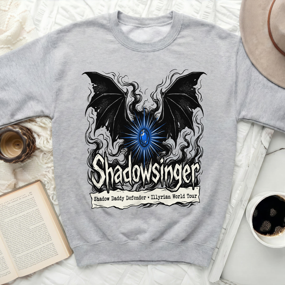 Light gray crewneck sweatshirt featuring a black winged graphic, glowing blue gem, and Shadowsinger text.