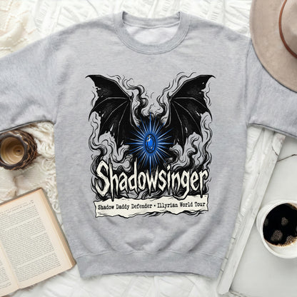 Light gray crewneck sweatshirt featuring a black winged graphic, glowing blue gem, and Shadowsinger text.