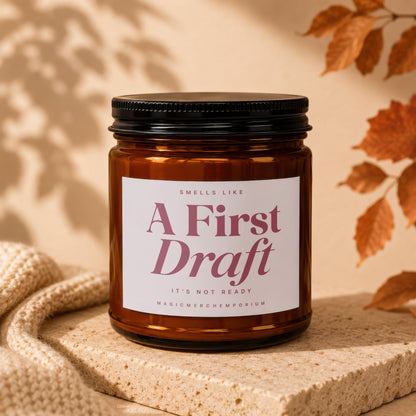 Brown jar candle, "A First Draft" text, with knit fabric and leaves.