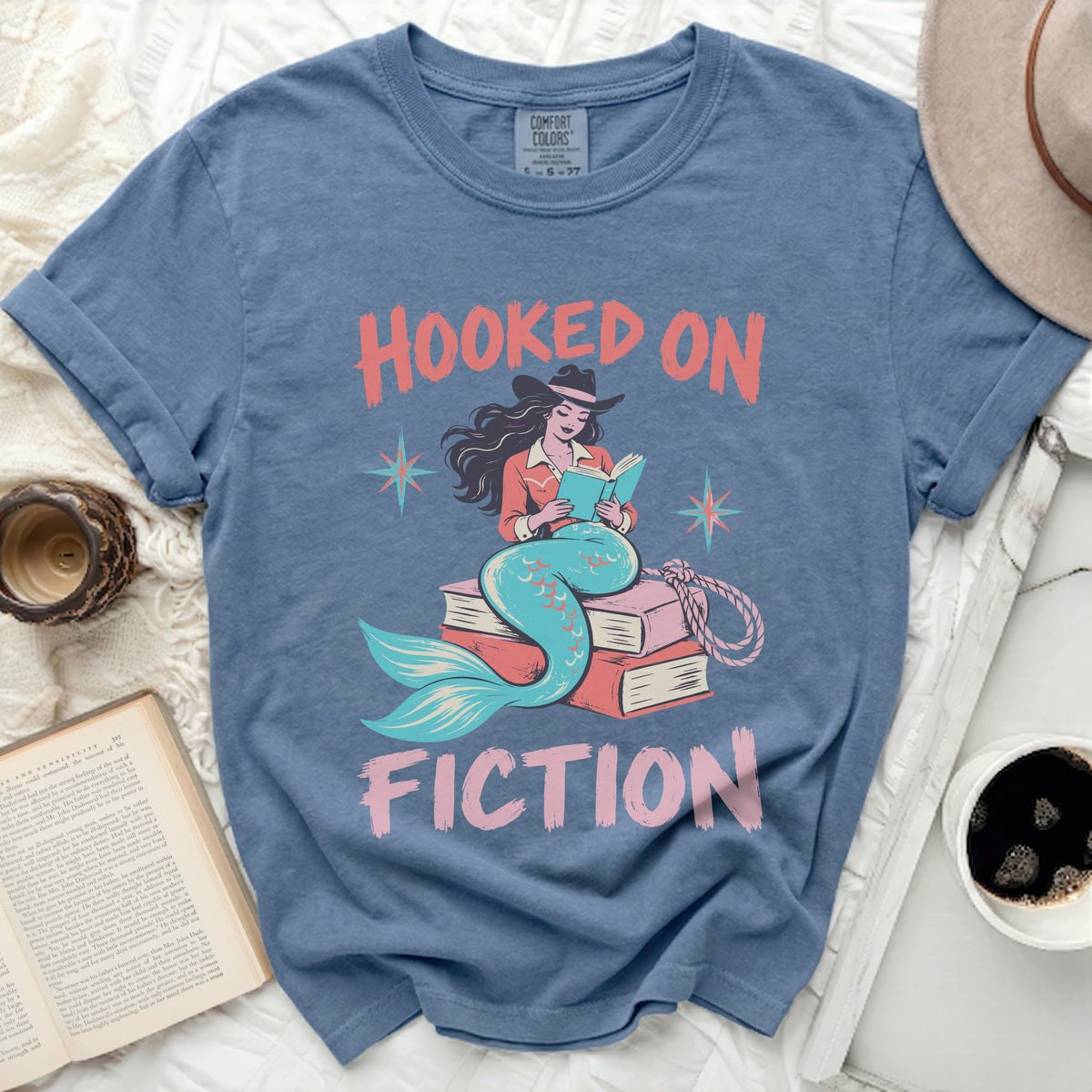 Mermaid reading book, "Hooked on Fiction" graphic on a blue t-shirt.