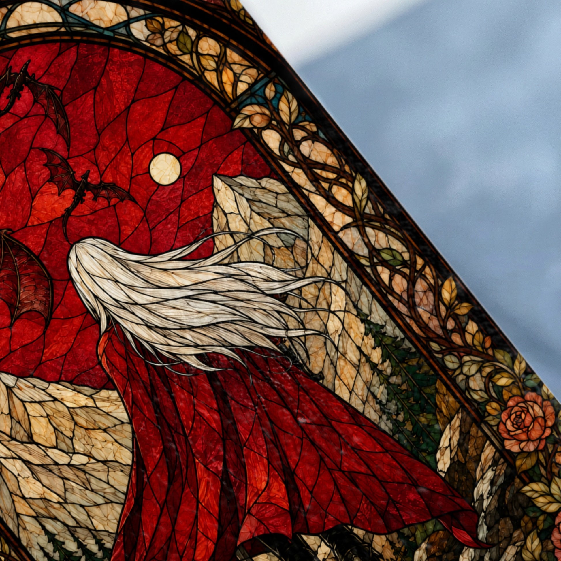 Stained glass scene of a blonde figure in a red cloak with dragons flying past a moon.