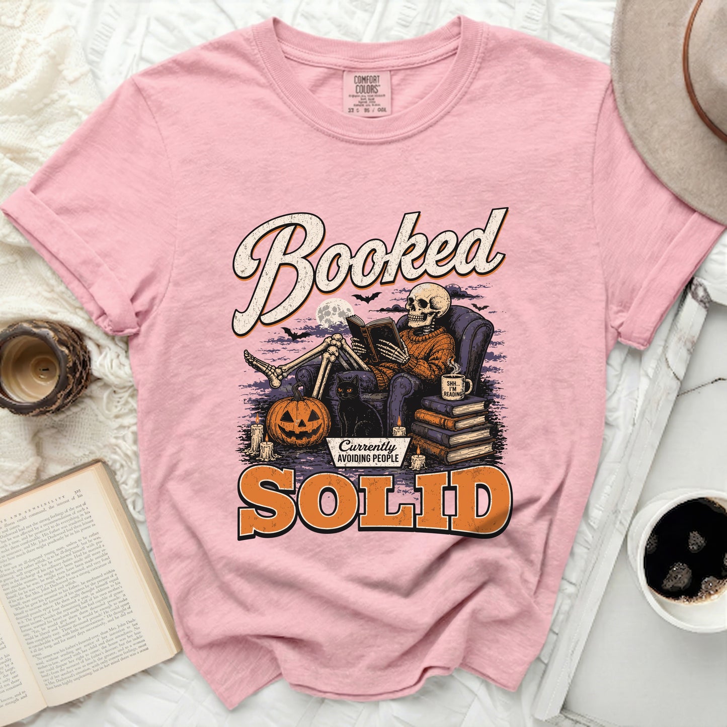 Textile graphic of skeleton reading book, saying "Booked" and "SOLID Currently Avoiding People".