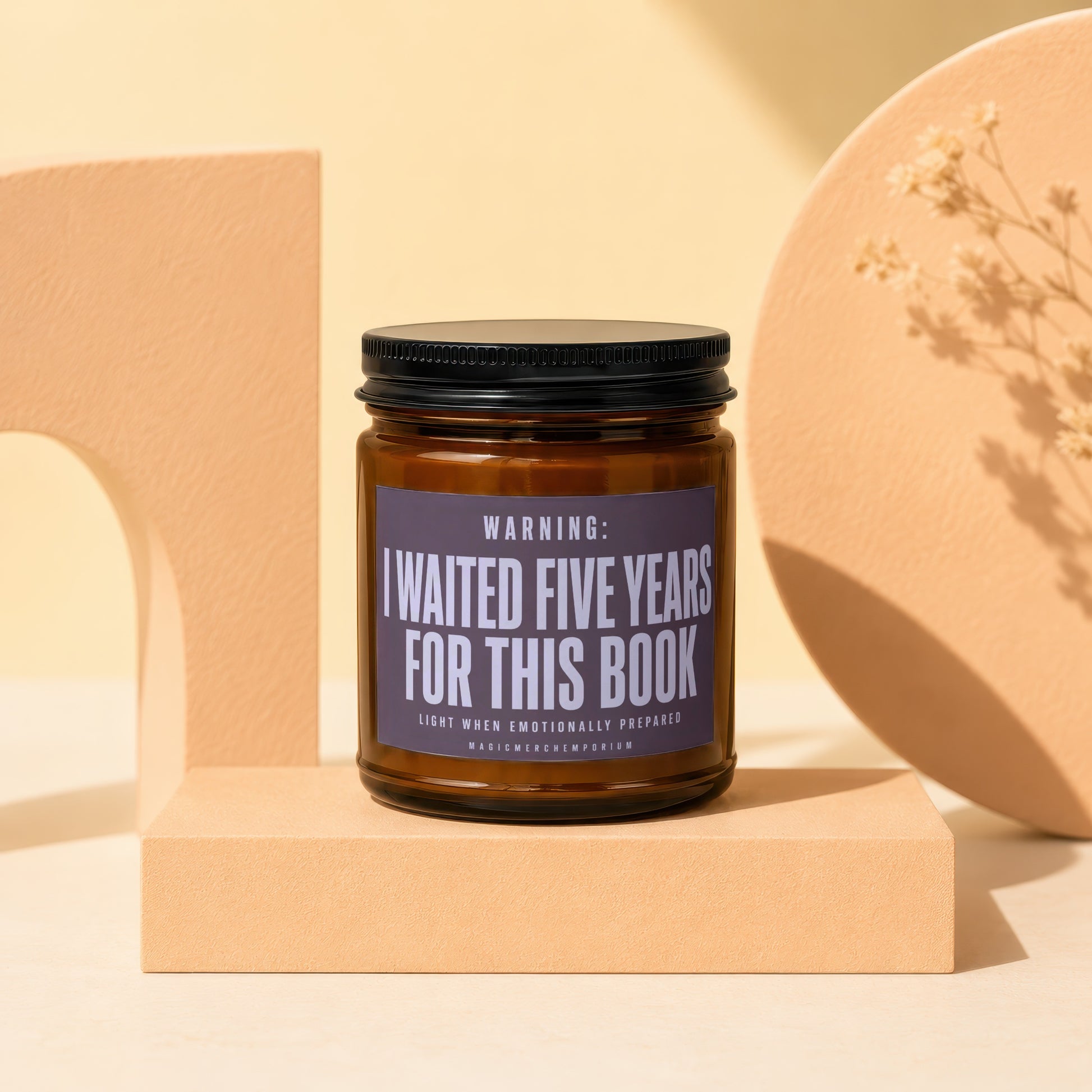 Amber jar candle with black lid reading "I WAITED FIVE YEARS FOR THIS BOOK".