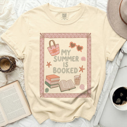 T-shirt with "My Summer is Booked" text, sunglasses, and beach bag.