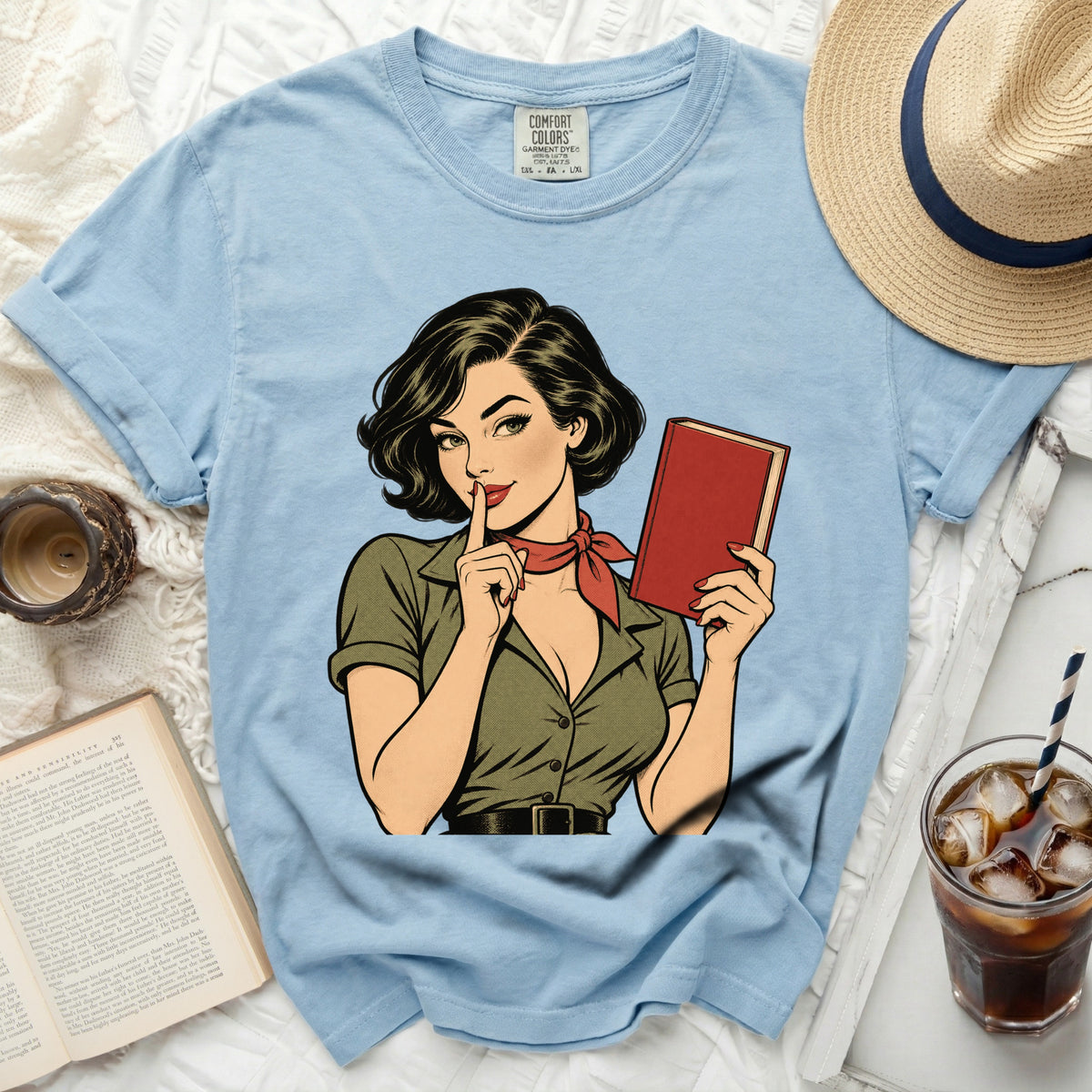 Light blue t-shirt featuring a retro comic book illustration of a woman holding a book.