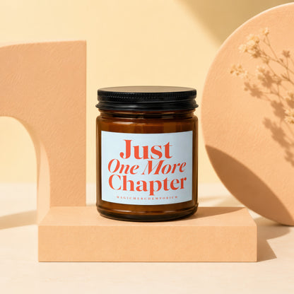 Amber candle with white label reading "Just One More Chapter" by MagicMerchEmporium.