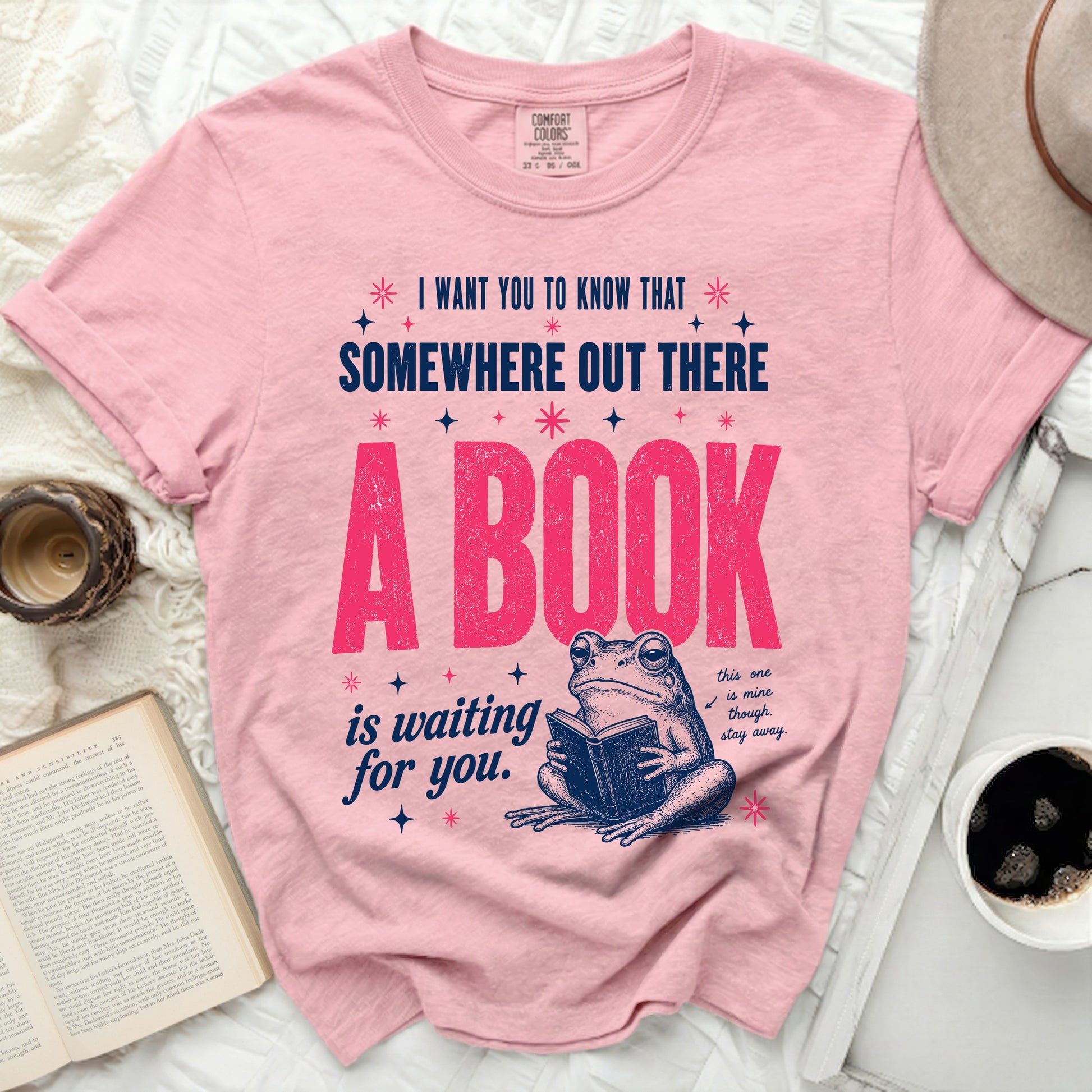 Pink t-shirt with frog reading a book and "A BOOK is waiting for you" text.