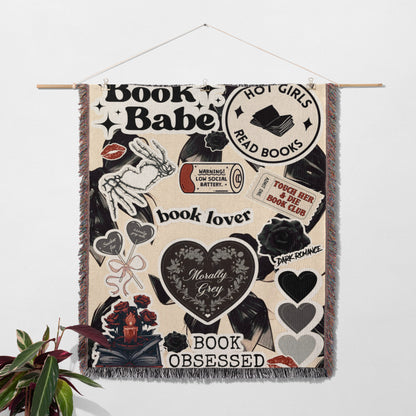 The image is a wall hanging featuring various book-related items and phrases, including the words "Book BABE", "Hot Girls Read Books", "book lover", "Morally Grey", "Dark Romance", and "Book Obsessed".