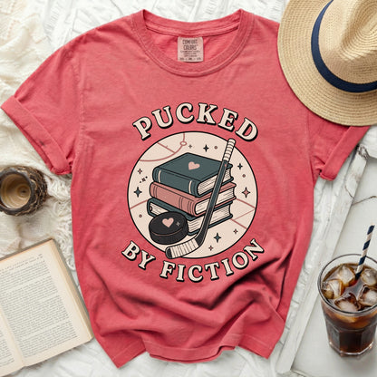Coral t-shirt with "Pucked By Fiction" text and hockey puck with books.