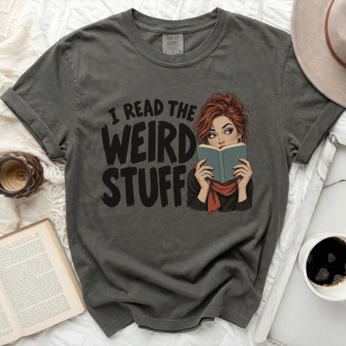 T-shirt with graphic of woman reading and text "I READ THE WEIRD STUFF".