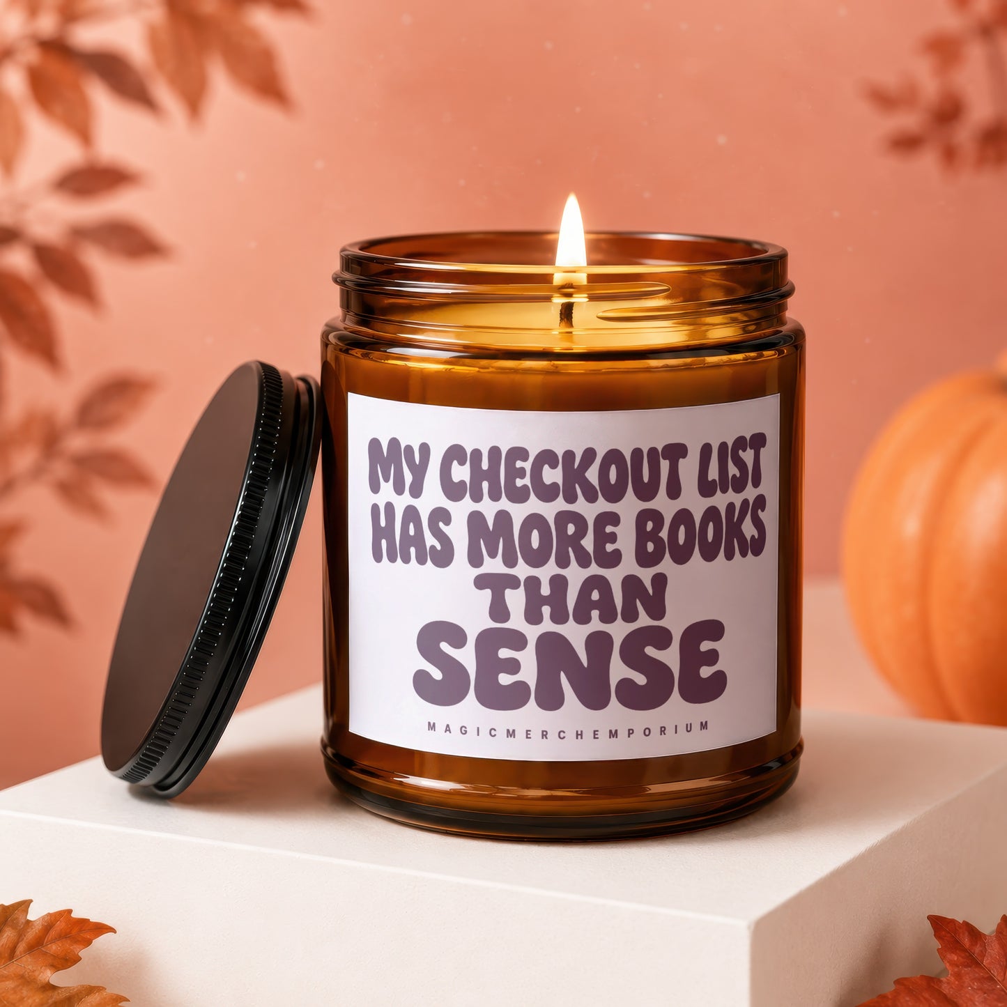 Amber candle with lit wick, lid off, reads "My checkout list has more books than sense."