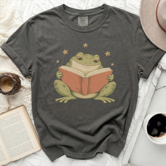 Dark grey Comfort Colors t-shirt with a graphic of a smiling frog reading a book.