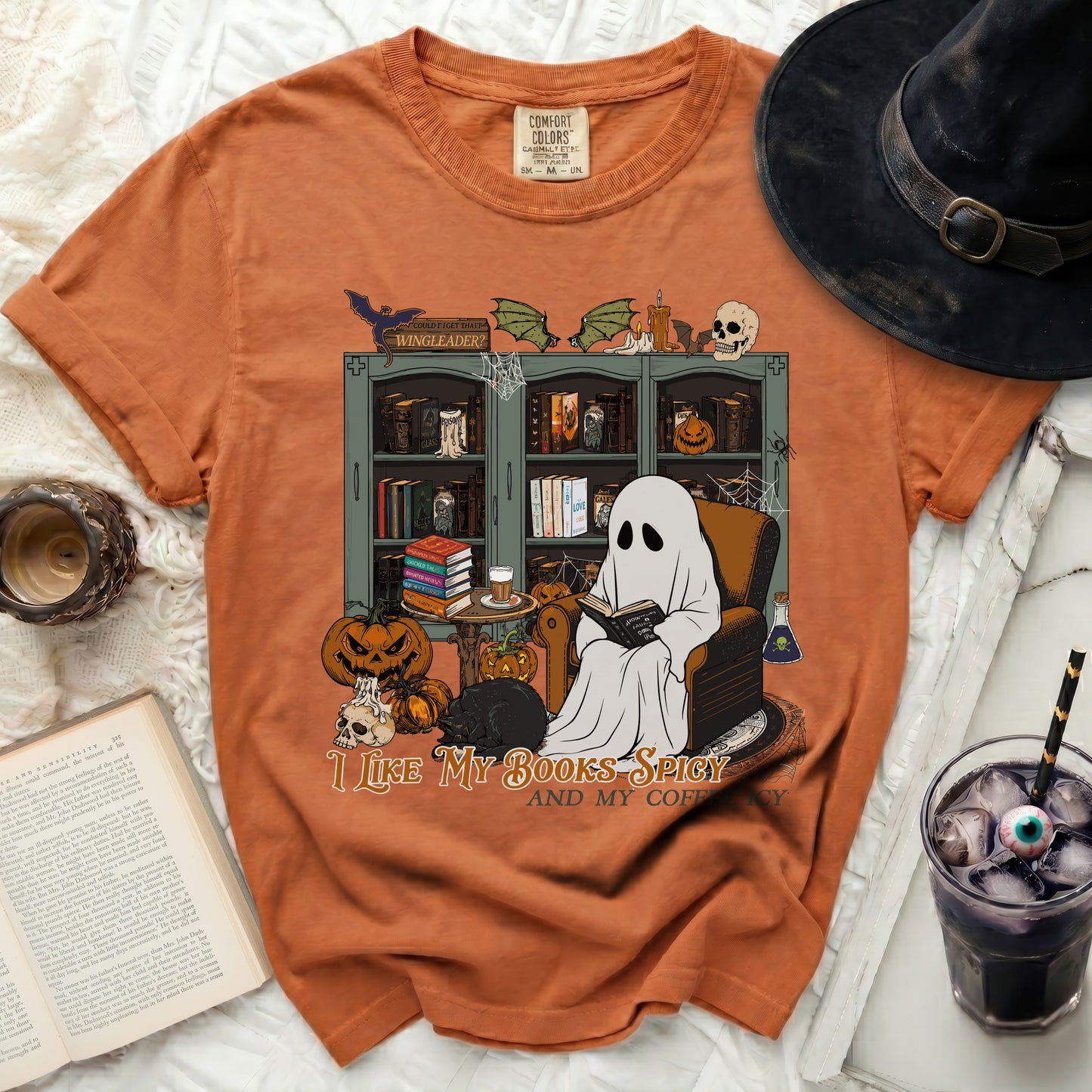 Ghost reading book with pumpkins, saying "I like my books spicy and my coffee".