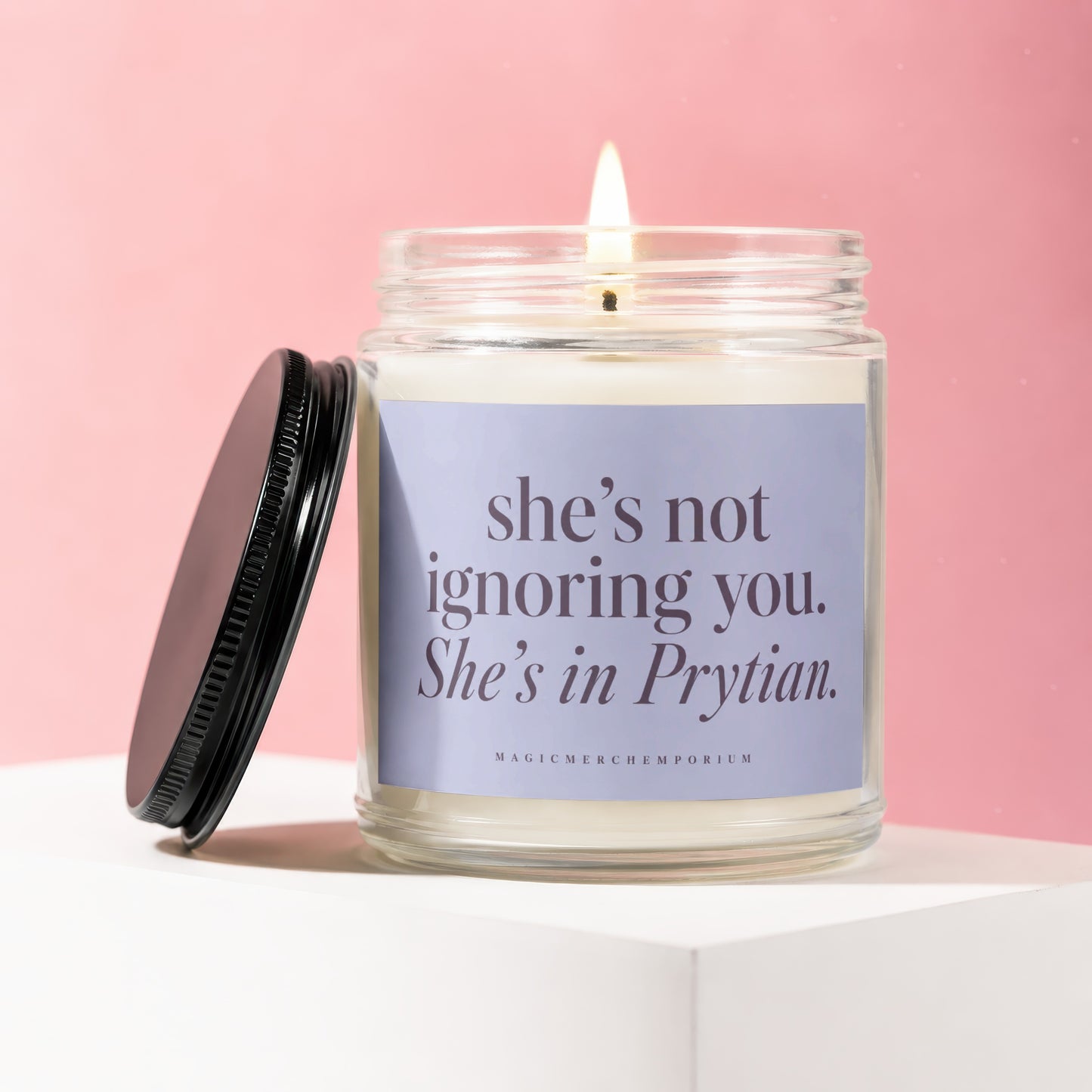 Candle in glass jar with black lid, reading "she's not ignoring you. She's in Prytian."