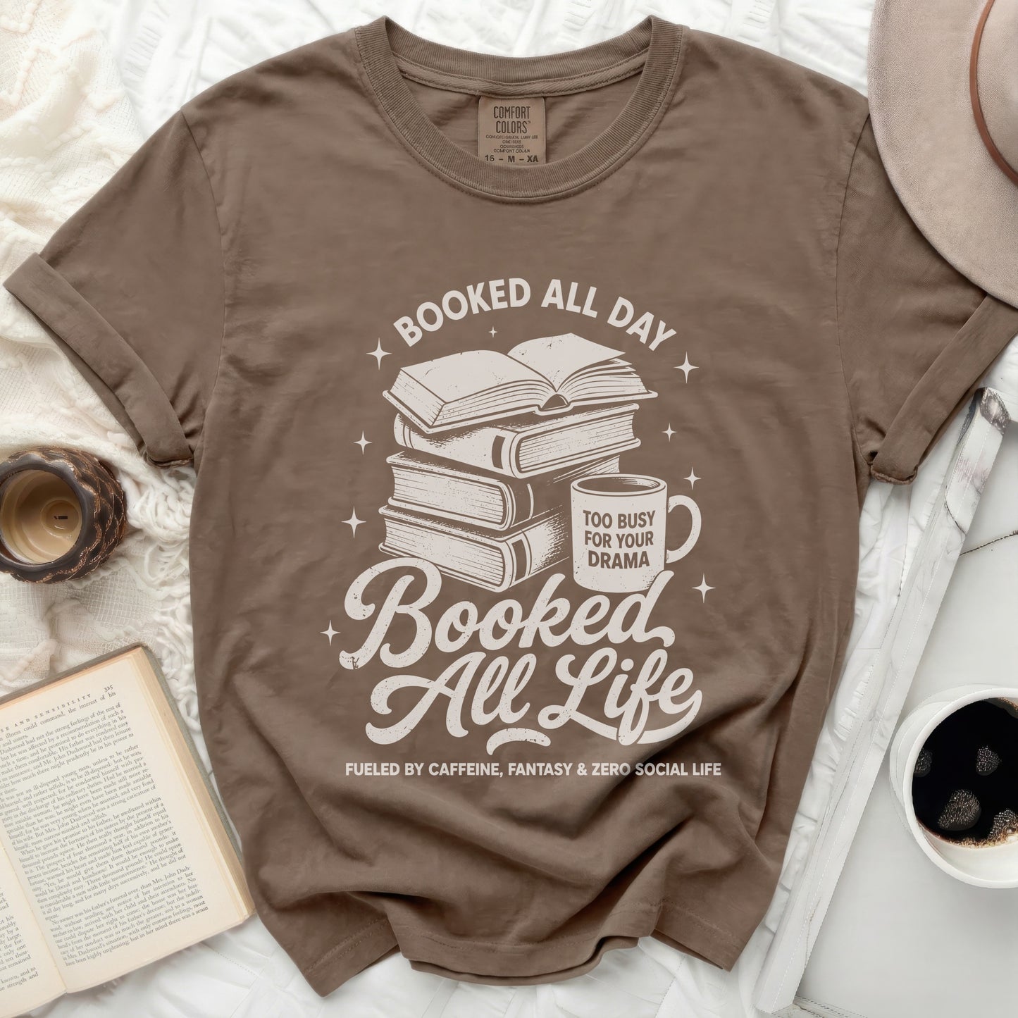 Brown t-shirt with stacked books, mug, and text "Booked All Day" "Booked All Life".