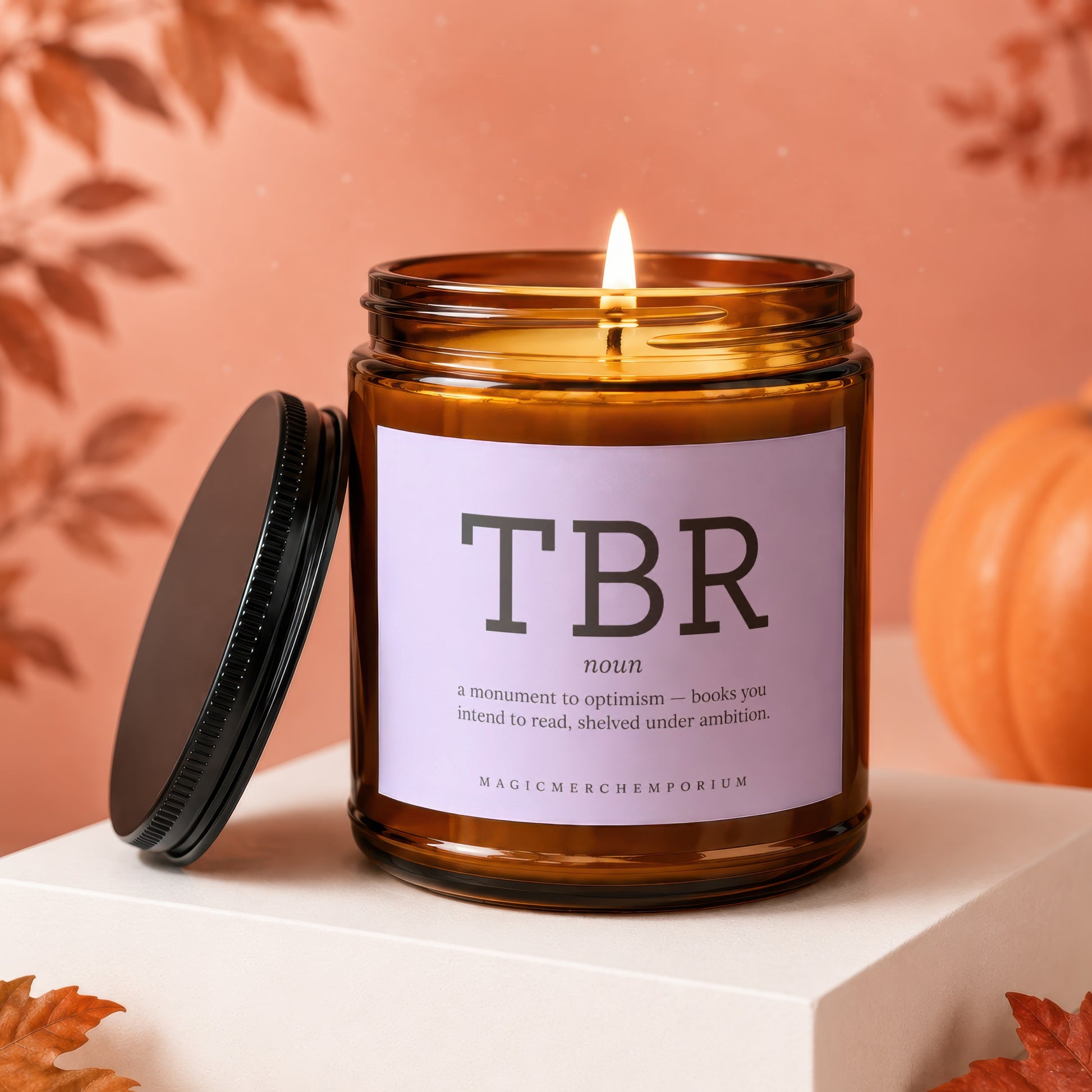 Amber jar candle with "TBR noun: a monument to optimism" text on lavender label.