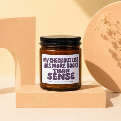 Amber candle with black lid, "My checkout list has more books than sense" text.