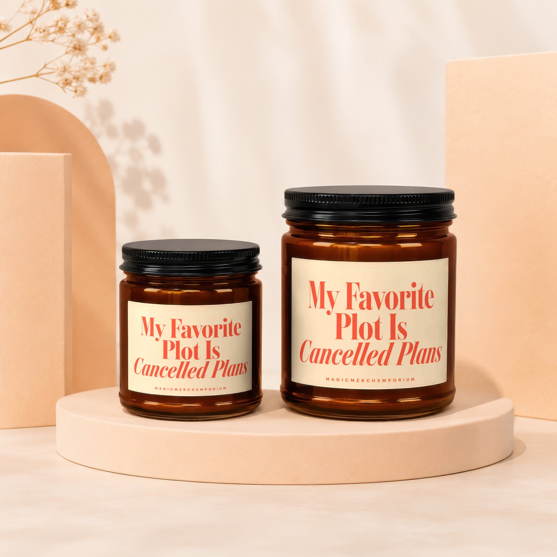 Two amber glass candles with cream labels saying "My Favorite Plot Is Cancelled Plans".