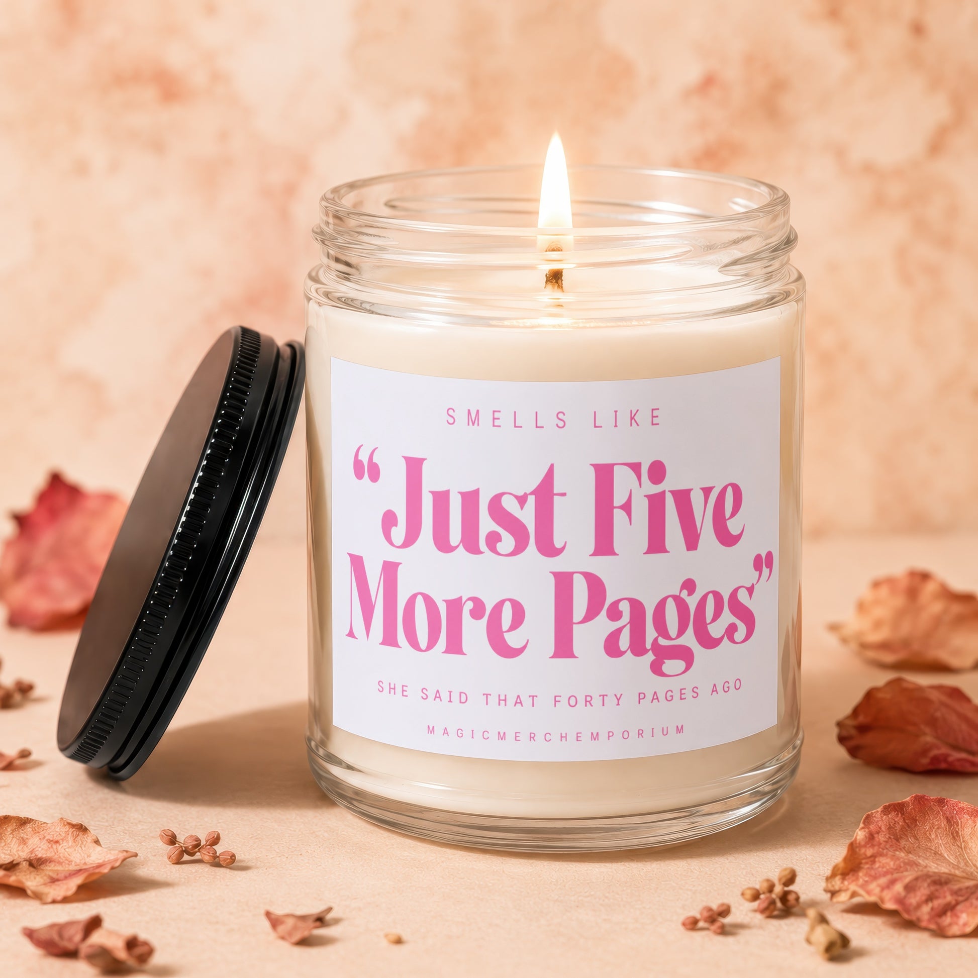 Scented candle with "Just Five More Pages" text, lid off, and dried leaves.
