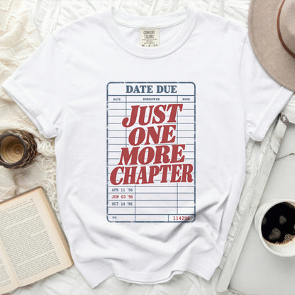 White t-shirt with "DATE DUE" and "JUST ONE MORE CHAPTER" library card graphic.